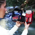 Red Survival Handy First Aid kit opened outdoors by a creek with emergency supplies — Adventure Awaits