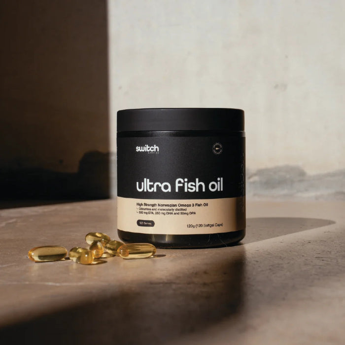Switch Nutrition Ultra Fish Oil tub with golden omega-3 softgel capsules in sunlight — Adventure Awaits