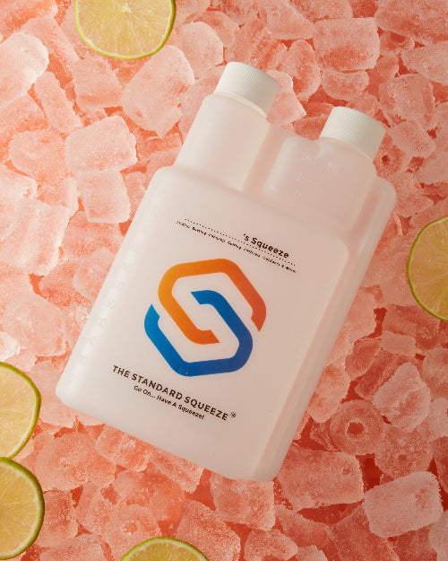 Standard Squeeze Bottle resting on crushed ice with fresh lime slices — Adventure Awaits