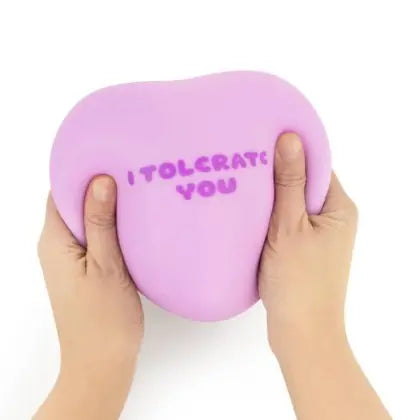 Hands squeezing lilac The Big Squij heart squishy with I Tolerate You message Adventure Awaits