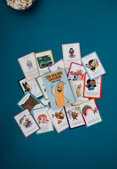 The Golden Sausage card game surrounded by colourful character cards on a teal background — Adventure Awaits