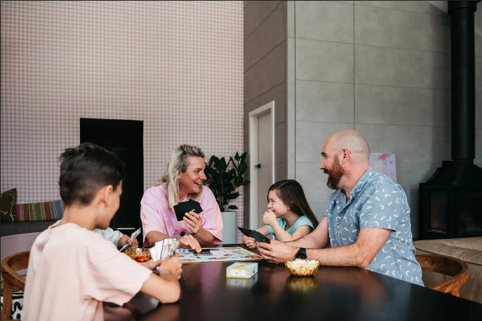 Family playing The Golden Sausage card game together at a table with snacks — Adventure Awaits