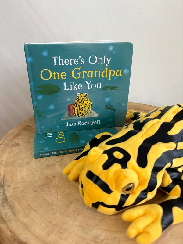 There’s Only One Grandpa Like You book beside a yellow and black frog plush toy — Adventure Awaits
