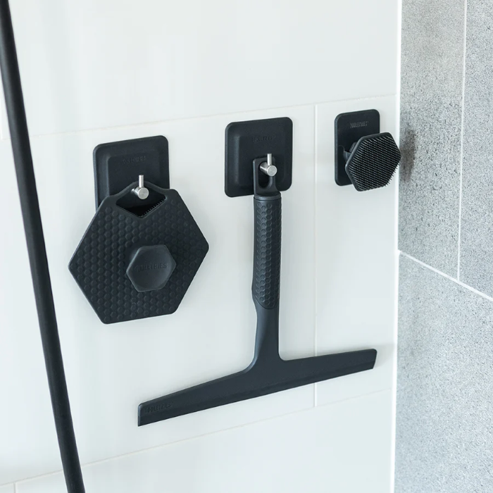 Tooletries squeegee on hook in shower wall with scrubbers on hooks