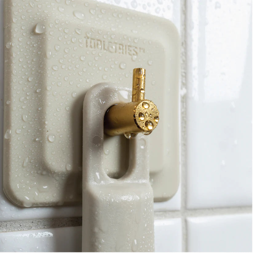 Cream shower mirror wall hook close-up with water droplets and brass razor holder — Adventure Awaits
