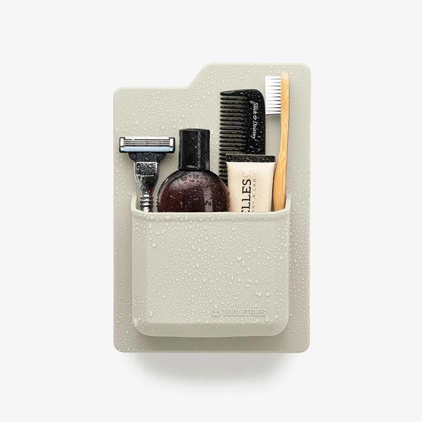 Cream shower organiser holding razor, comb, toothbrush and toiletries — Adventure Awaits