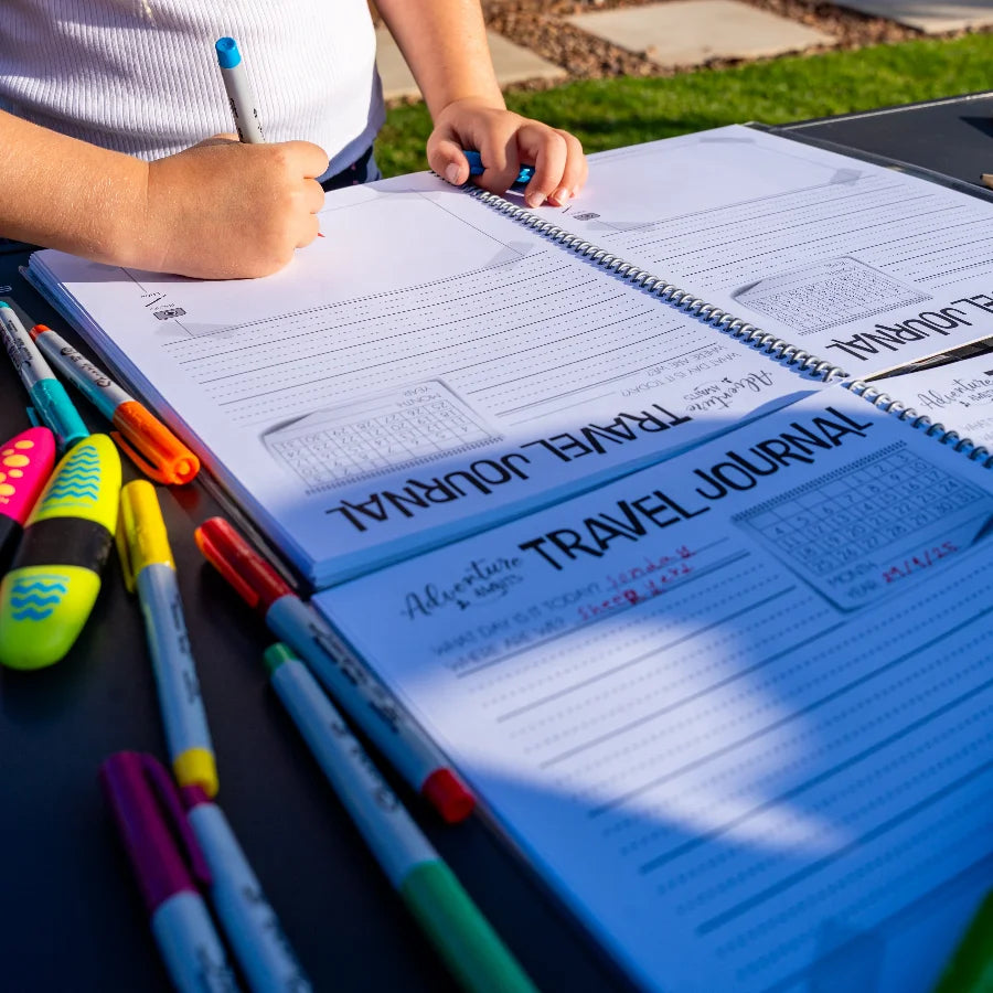 Spiral bound Kids travel journal on outside table with colourful texters 