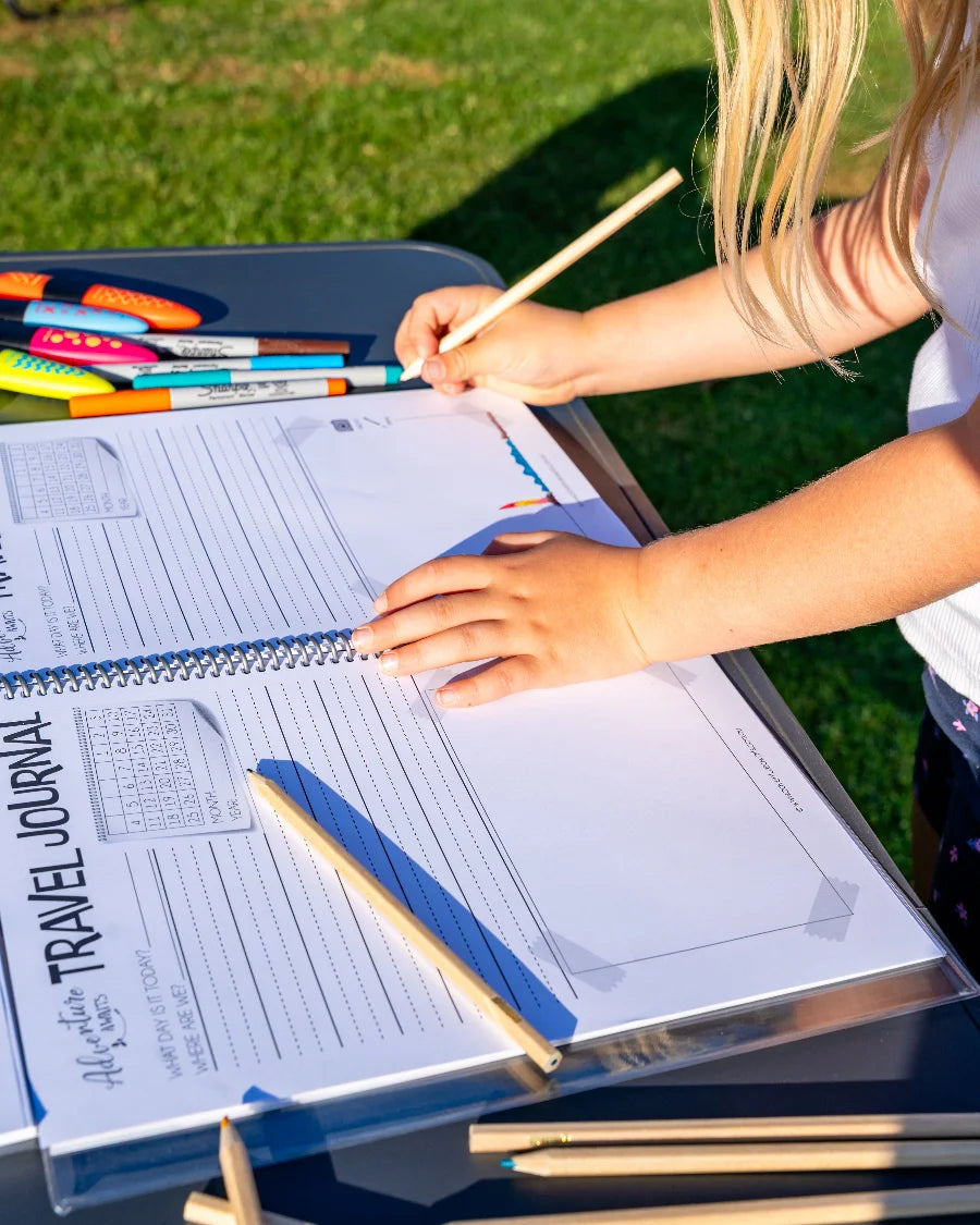 Young girl with pencil drawing her kids travel journal 