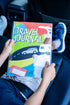 Kid holding our kids travel journal in the car 