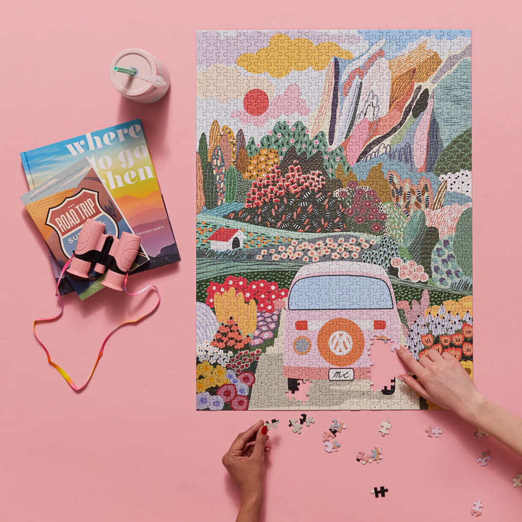 Werkshoppe Road Trip Puzzle being put together with books and binoculars next to it