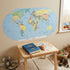 World map wall sticker in a kids' playroom above a wooden table with journal, pencils and toys — Adventure Awaits