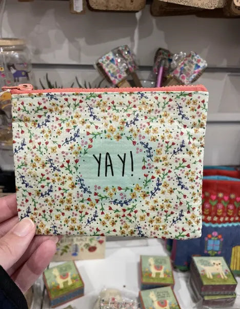 YAY! mini recycled zip pouch with floral print held in store display — Adventure Awaits