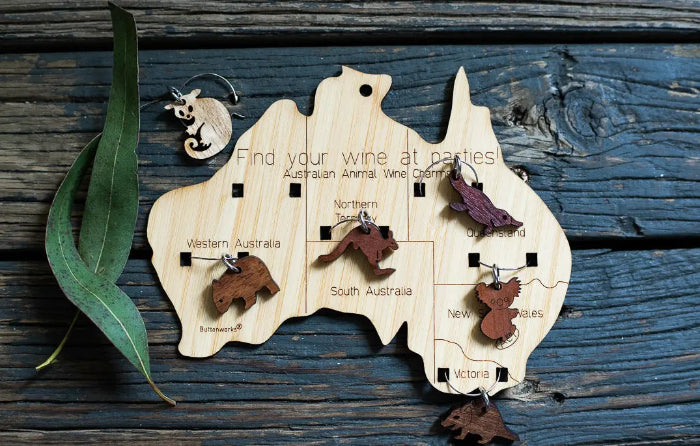 Australia-shaped wooden wine charm set with native animal markers displayed on rustic timber — Adventure Awaits
