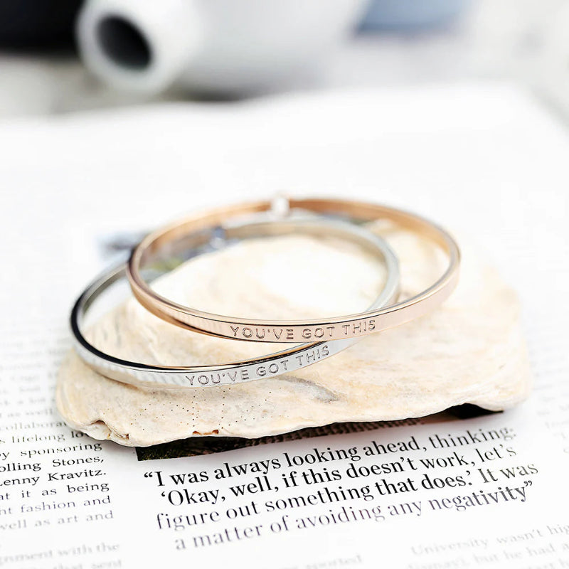 Two silver rings with 'You've Got This' engraving on a piece of paper.