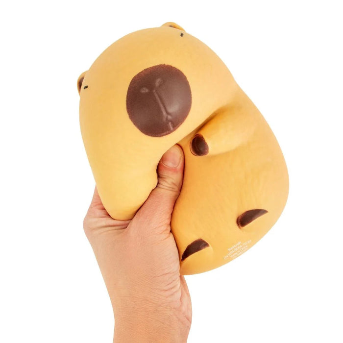 Hand squeezing The Big Squii jumbo capybara squishy with tan body and brown details — Adventure Awaits