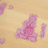 Partially completed pink Penis Puzzle with cheeky illustrated jigsaw pieces on a timber table — Adventure Awaits