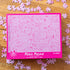 Pink 1000-piece Penis Puzzle box surrounded by matching jigsaw pieces with cheeky illustrated designs — Adventure Awaits