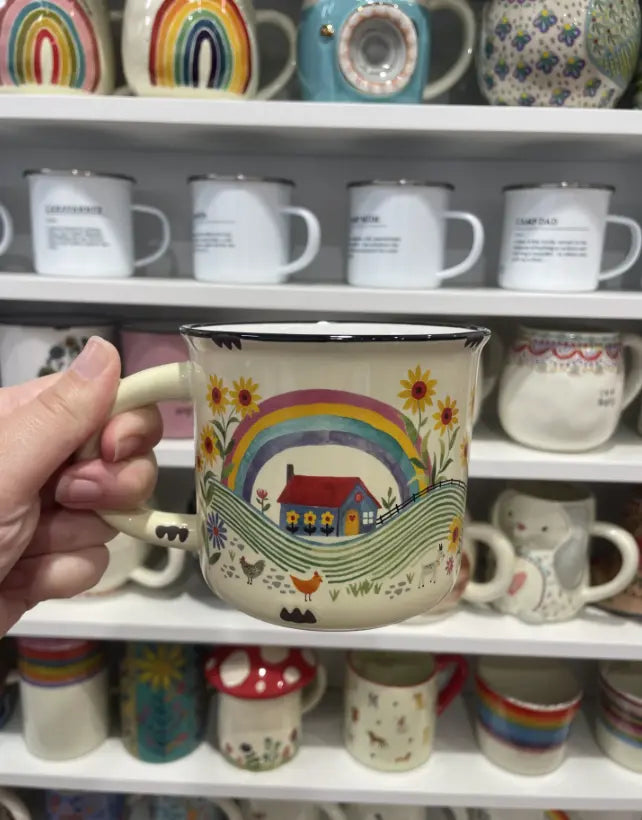 Hand holding a Let’s Move to the Country camp mug with rainbow, cottage and chickens — Adventure Awaits
