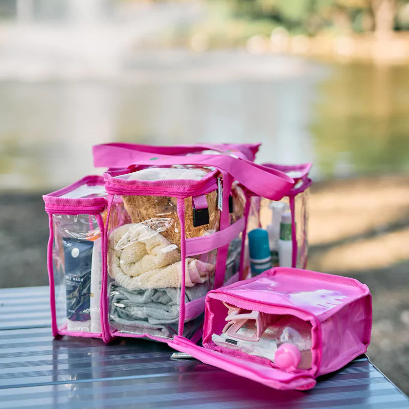 Pink Campaq clear toiletry storage bag and detachable pocket on a lakeside camping table — Adventure Awaits