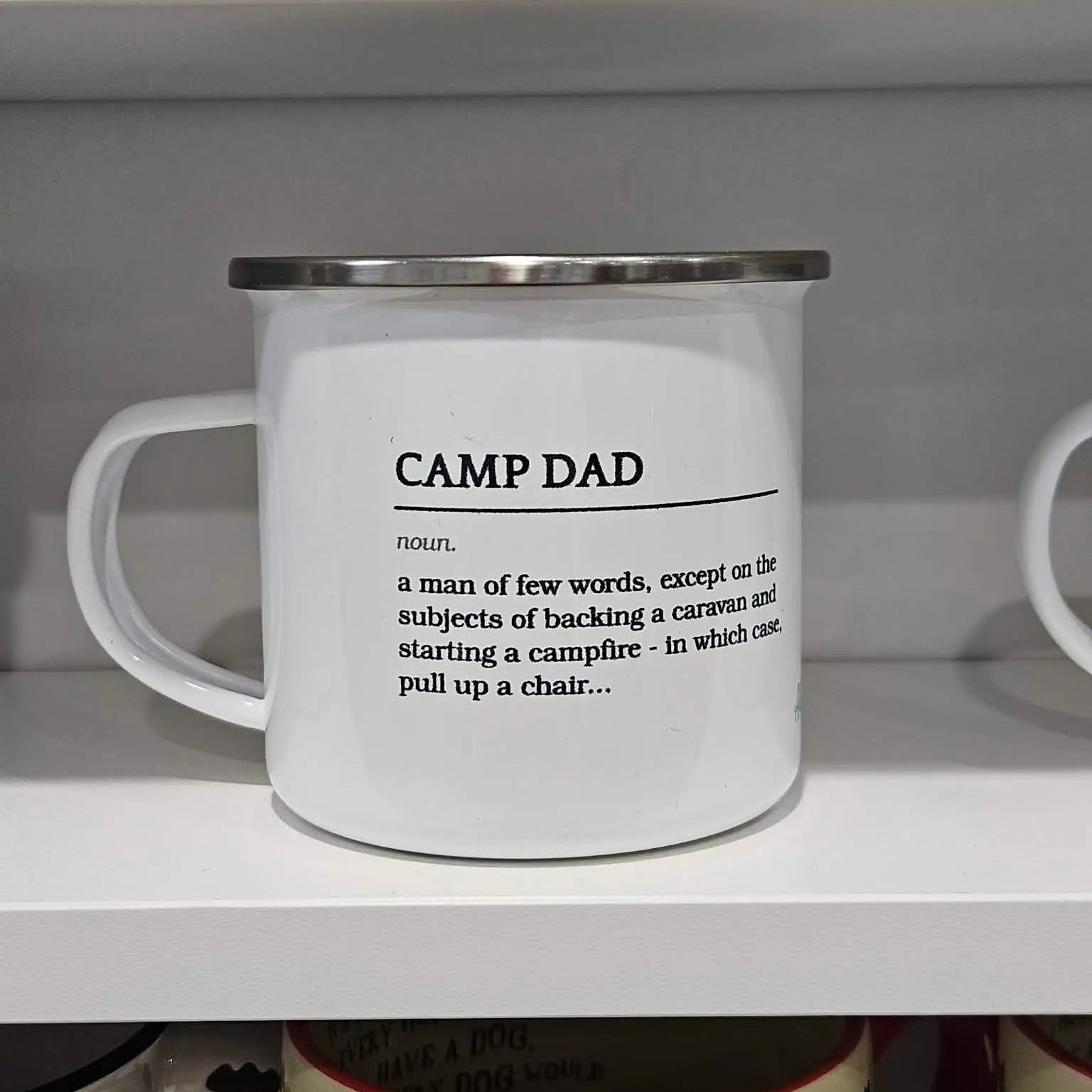 Mug with 'Camp Dad' definition on a shelf with decorative items.