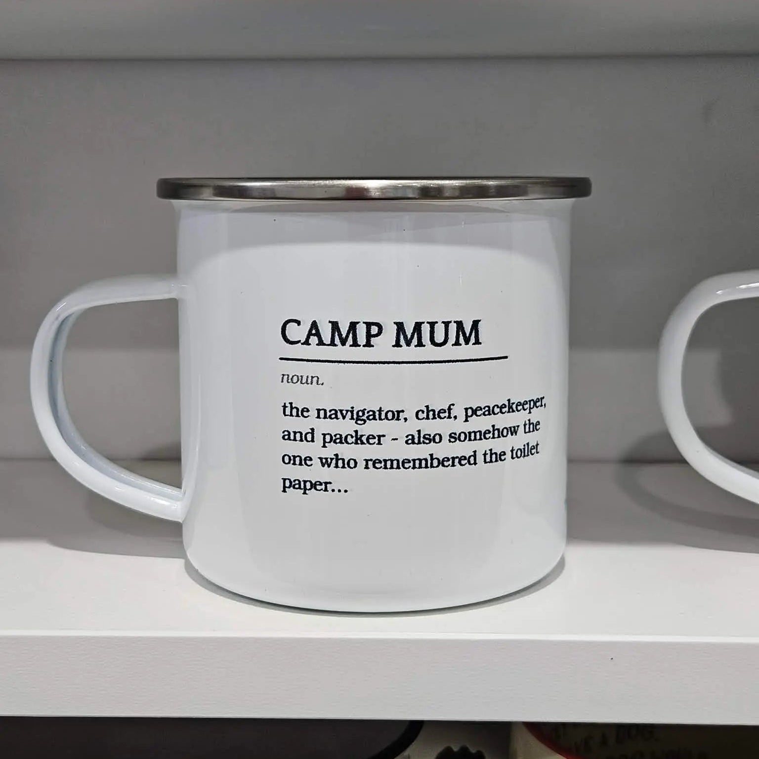 White mug with 'CAMP MUM' definition text on a shelf