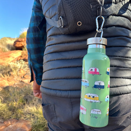 Person holding a green water bottle with camper design outdoors