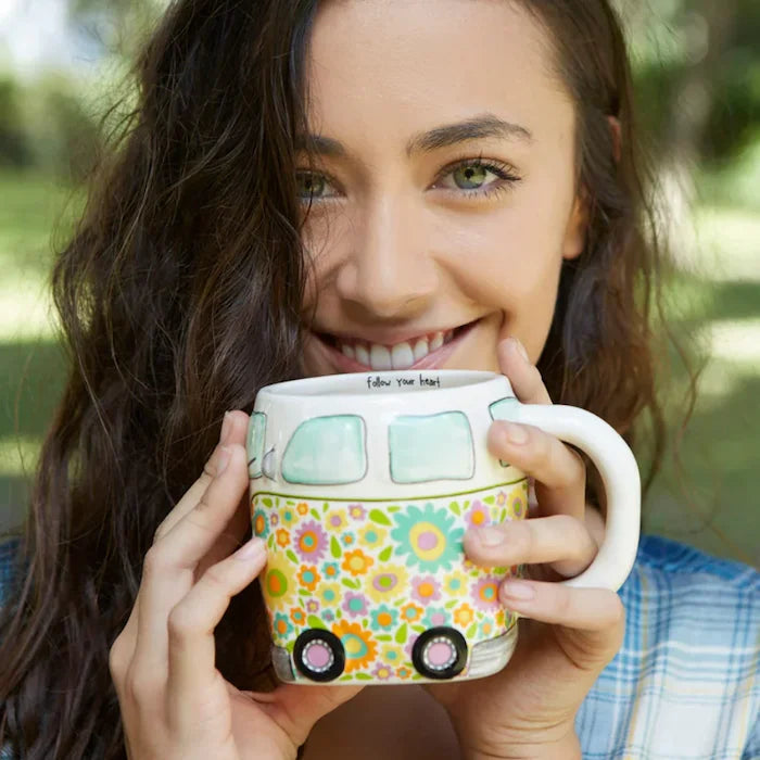 Woman holding a colourful caravan mug with a floral van design outdoors