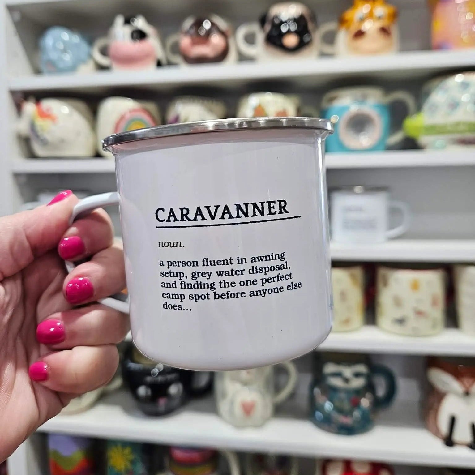 Hand holding a "Caravanner" definition enamel mug in the Adventure Awaits gift shop, Numurkah Victoria — Adventure Awaits