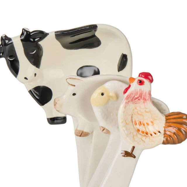 Close-up of ceramic cow, pig, sheep and rooster measuring spoons with hand-painted details — Adventure Awaits