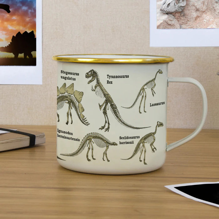 Cream enamel dinosaur mug with gold rim on desk, skeleton illustrations and study notes Adventure Awaits