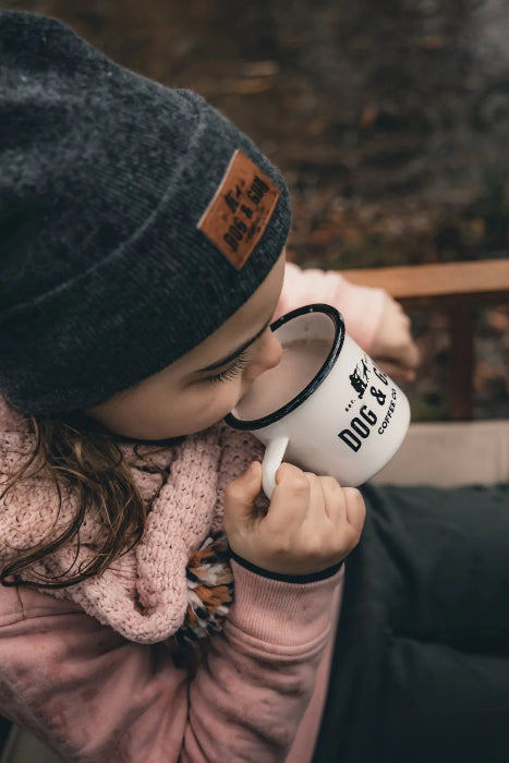 Child sipping Dog & Gun hot chocolate from enamel camp mug outdoors — Adventure Awaits