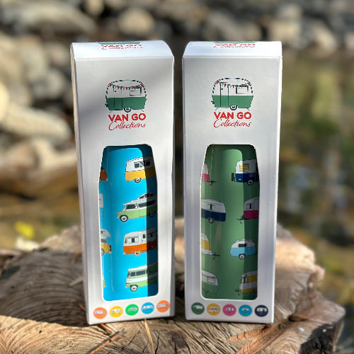 Two Van Go Collections water bottles in their packaging on a wooden surface with a natural background.