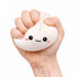 Hand holding a cute white lucky bao bun-shaped stress reliever with a face on a white background