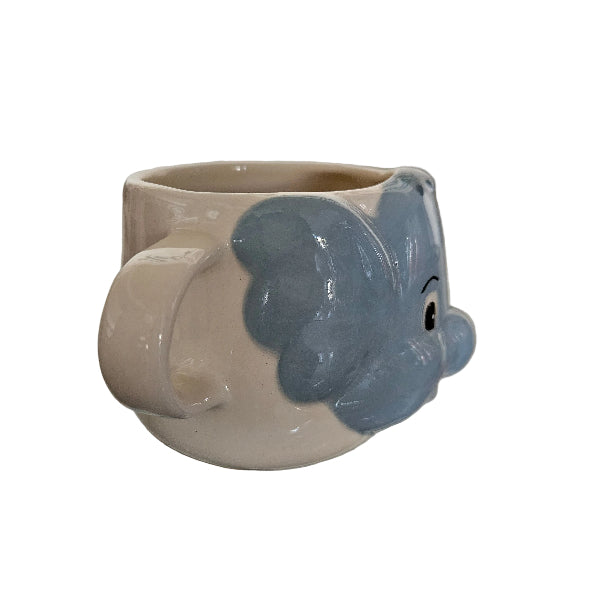 Ceramic elephant shaped object on a white surface with a blurred background