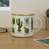 enamel mug with botanical cactus illustrations and gold rim on desk, stylish drinkware for home, office or camping use Adventure Awaits