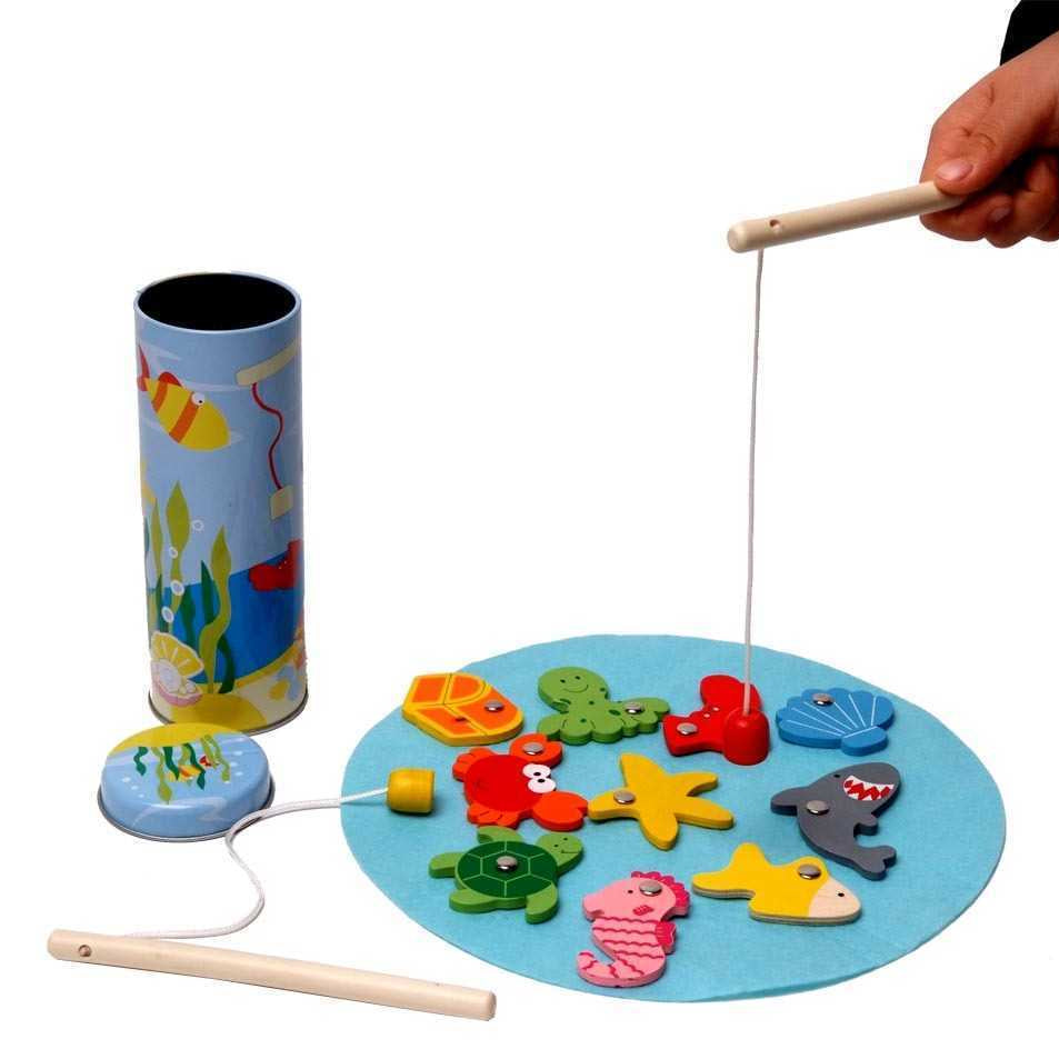Wooden fishing game with colorful fish magnets on a blue board, held by a hand with a rod.