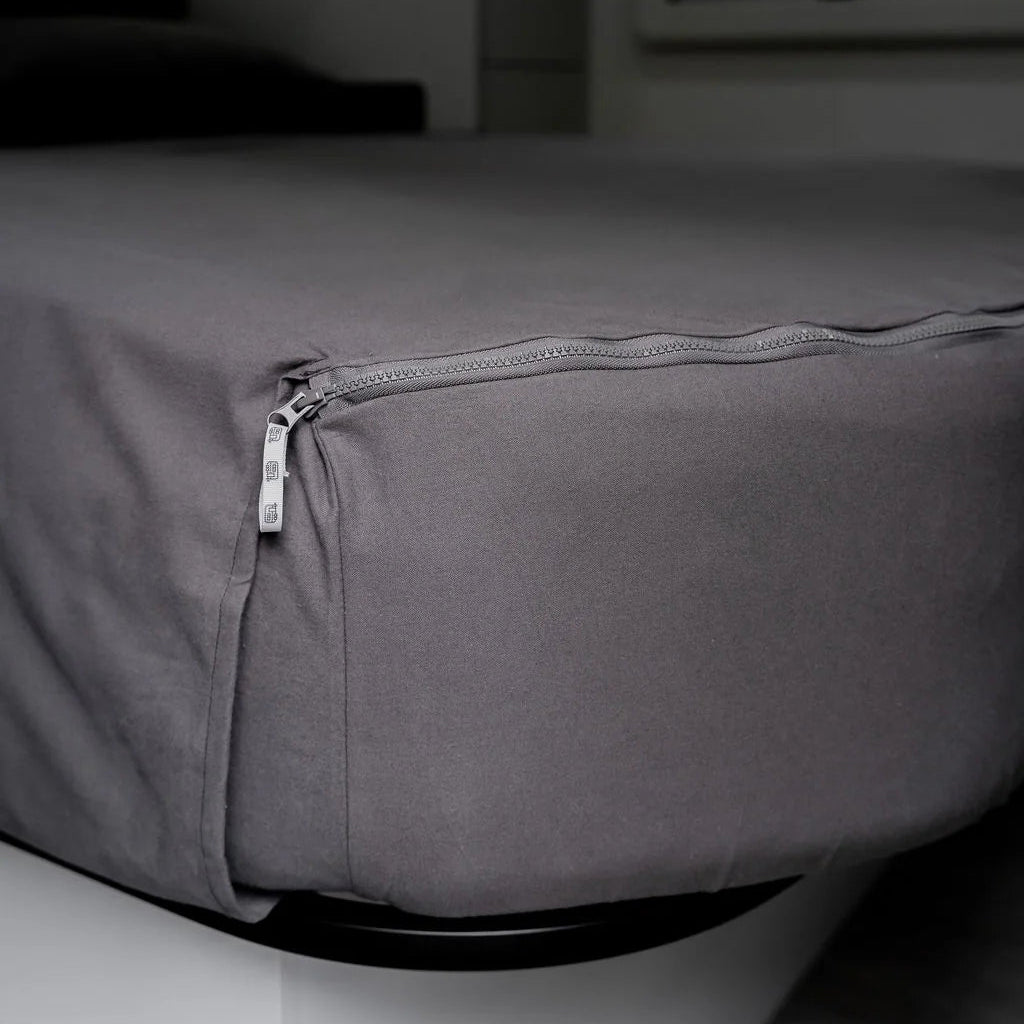 Close-up of MeanderWild caolmine grey flannelette fitted sheet corner with zipper closure on a caravan bed — Adventure Awaits