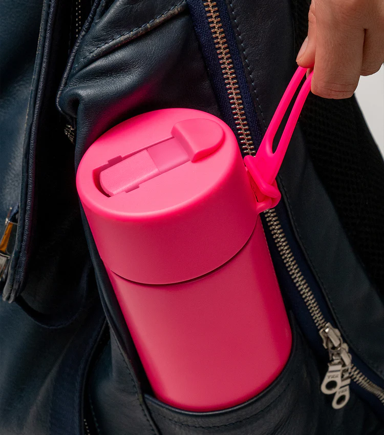 pink Frank Green bottle with flip straw lid and strap tucked in backpack pocket — Adventure Awaits