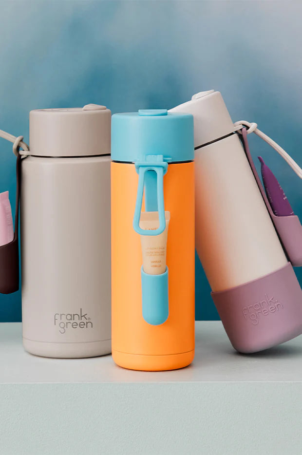Frank Green reusable bottles with clip-on lip gloss holders in pastel colours and bright orange with blue top and holder — Adventure Awaits