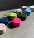 Assorted colourful Frank Green bottle lids with matching straps on concrete — Adventure Awaits