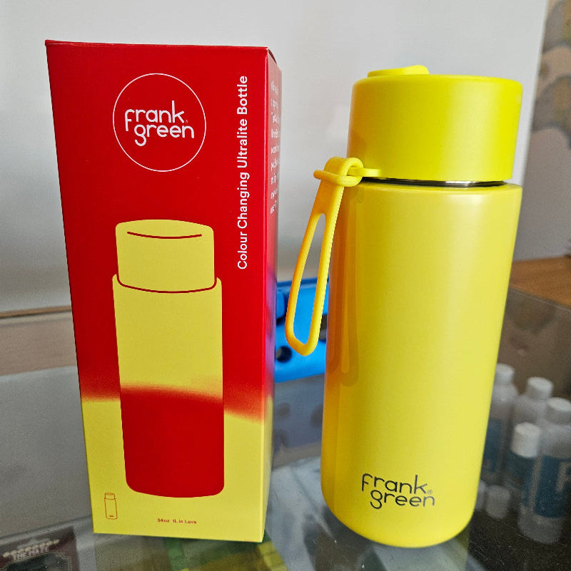 Yellow thermos with 'frank Green branding next to a red box on a white surface.