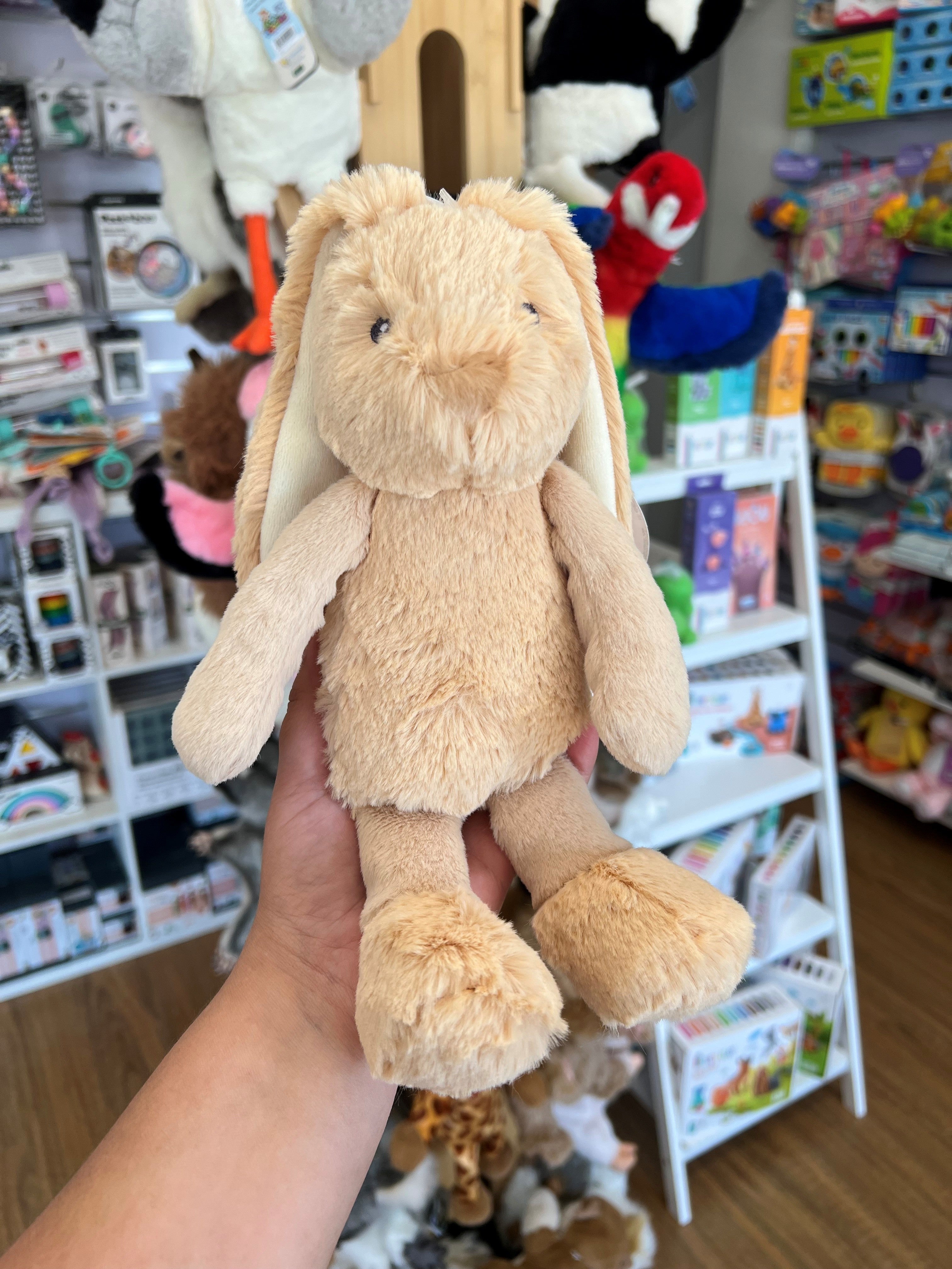 beige frankie bunny in beige in hand with shop in background