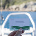 Hand holds a Getting Lost Fishing Edition card prompting anglers to follow birds to the next fishing spot, Adventure Awaits
