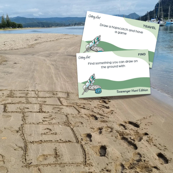 Scavenger Hunt Edition cards over beach hopscotch drawn in sand for outdoor travel play — Adventure Awaits