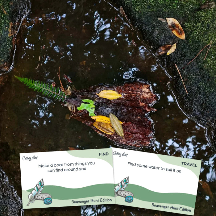 Scavenger Hunt Edition cards beside a bark boat floating in creek water for outdoor play — Adventure Awaits