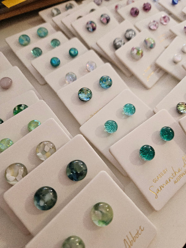 Display of various gemstone earrings on white cards.