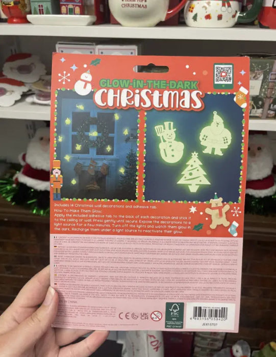 Hand holding back of Glow-in-the-Dark Christmas wall decorations pack with instructions and glowing examples — Adventure Awaits