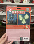Hand holding back of Glow-in-the-Dark Christmas wall decorations pack with instructions and glowing examples — Adventure Awaits