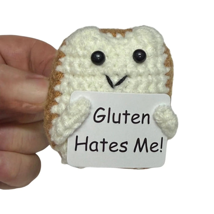 hand holding a handmade crochet toast plush toy with a humorous “Gluten Hates Me!” sign