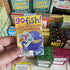 Hand holding a 'gofish!' card game box with other board games in the background.